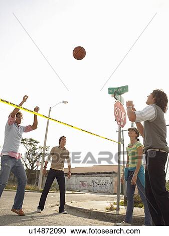 Stock Image - Friends playing volleyball over police tape in street. Fotosearch