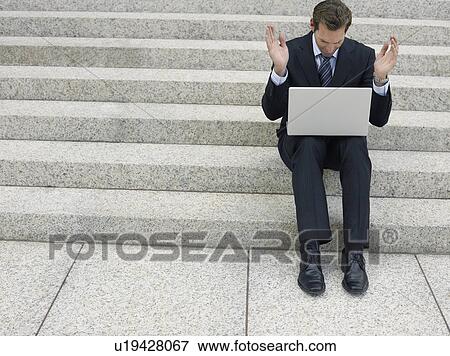 Stock Photo - Frustrated businessman using laptop on steps. Fotosearch