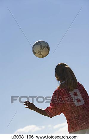 Stock Photograph - Girl (13-17) heading soccer ball, back view. Fotosearch