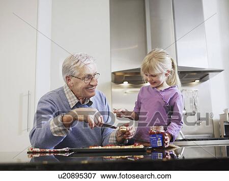Girl (3-4) and grandfather spreading jam on biscuits in kitchen View Large Photo Image Stock Photo - Girl (3-4) and grandfather spreading jam on biscuits in kitchen. Fotosearch