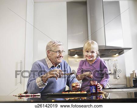 Girl (3-4) and grandfather spreading jam on biscuits in kitchen View Large Photo Image Stock Photo - Girl (3-4) and grandfather spreading jam on biscuits in kitchen. Fotosearch