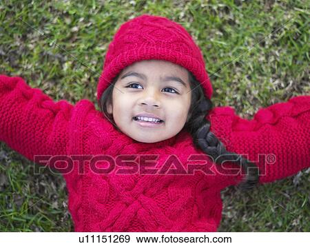 Stock Photo - Girl (3-4) lying in grass with arms extended, portrait, elevated view. Fotosearch