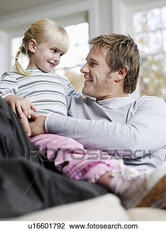 Girl (3-4) sitting in father's lap in house View Large Photo Image Stock Image - Girl (3-4) sitting in father's lap in house. Fotosearch