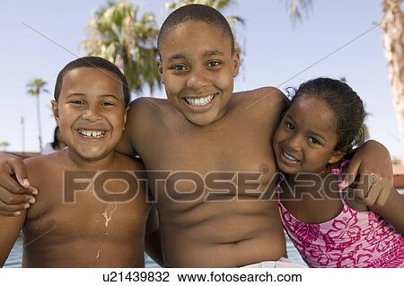 Stock Image - Girl (5-6), boy (7-9), boy (10-12) at swimming pool, front view portrait.. Fotosearch