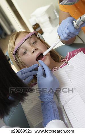 Stock Photography - Girl (7-10) having teeth examined at dentists. Fotosearch