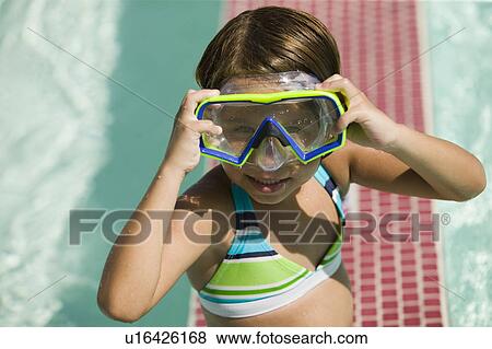 Girl (7-9) Adjusting Goggles in swimming pool, portrait. View Large Photo Image Stock Photo - Girl (7-9) Adjusting Goggles in swimming pool, portrait.. Fotosearch