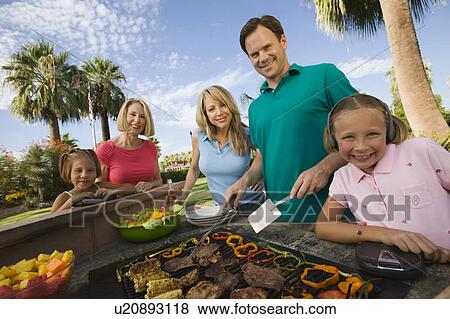 Girl (7-9) listening to portable music player at outdoor barbecue with sister (7-9), parents and grandmother, portrait. View Large Photo Image Stock Photo - Girl (7-9) listening to portable music player at outdoor barbecue with sister (7-9), parents and grandmother, portrait.. Fotosearch