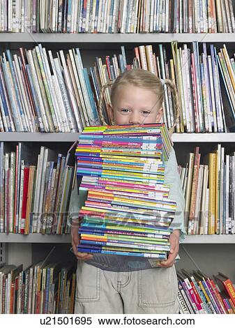 Stock Photography - Girl holding stack of books in library, portrait. Fotosearch