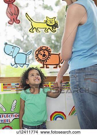 Picture - Girl holding teacher's hand in classroom. Fotosearch