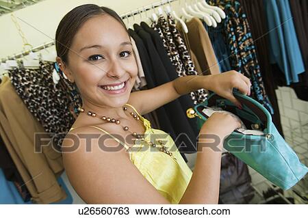 Stock Image - Girl Looking at Purse in Boutique, portrait. Fotosearch