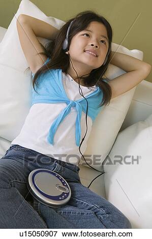 Stock Photo - Girl lying in bed Listening to Music on CD Player, close up. Fotosearch