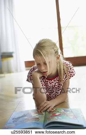 Stock Image - Girl lying on floor at home reading atlas. Fotosearch
