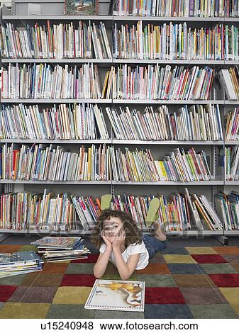 Stock Photo - Girl lying on stomach in front of library bookshelf. Fotosearch