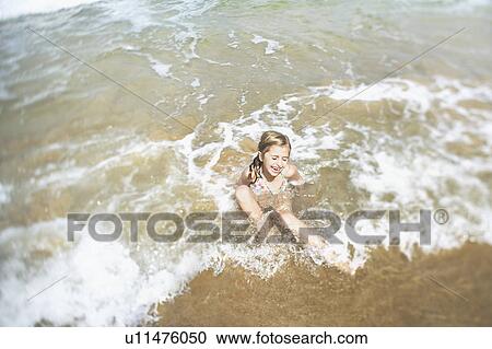 Stock Image - Girl playing in surf, elevated view. Fotosearch