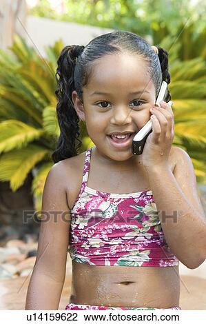 Stock Image - Girl sitting in back yard Using Cell Phone, front view. Fotosearch