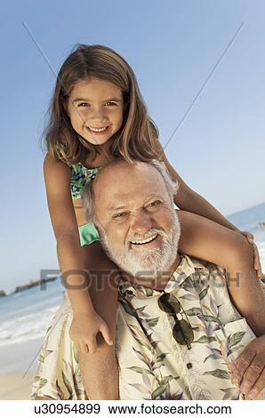 Girl sitting on grandfather's shoulders on beach View Large Photo Image Stock Photo - Girl sitting on grandfather's shoulders on beach. Fotosearch