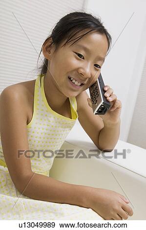 Girl sitting on sofa Talking on Cordless Telephone View Large Photo Image Stock Photo - Girl sitting on sofa Talking on Cordless Telephone. Fotosearch