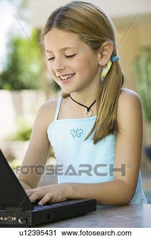 Stock Image - Girl Using Laptop on Outdoor Patio. Fotosearch