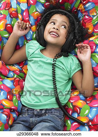 Girl wearing headphones reclining on beanbag, view from above View Large Photo Image Stock Photo - Girl wearing headphones reclining on beanbag, view from above. Fotosearch