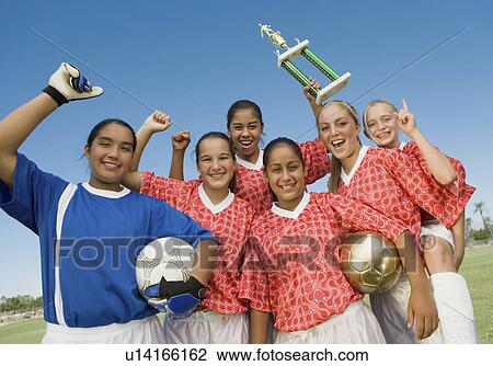 Stock Image - Girls' soccer team (13-17) holding trophy and celebrating, portrait. Fotosearch
