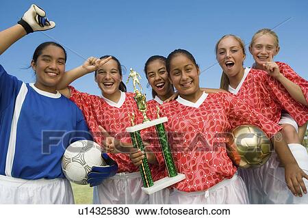 Stock Image - Girls' soccer team (13-17) holding trophy and celebrating, portrait. Fotosearch