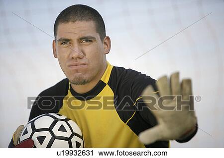 Stock Image - Goalkeeper holding ball, portrait. Fotosearch