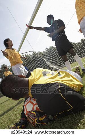 Picture - Goalkeeper on ground holding soccer ball while referee gives red card. Fotosearch