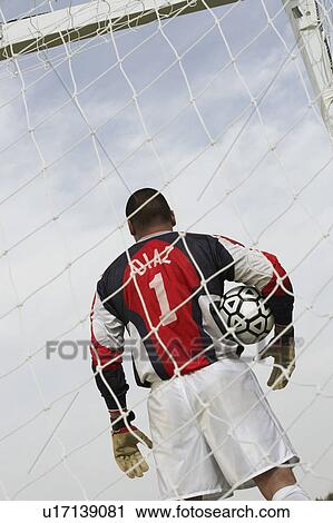 Goalkeeper standing in goal with ball, back view, low angle view View Large Photo Image Stock Image - Goalkeeper standing in goal with ball, back view, low angle view. Fotosearch