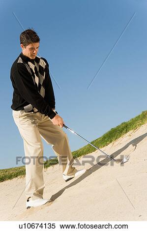 Stock Photography - Golfer hitting ball from sand trap. Fotosearch