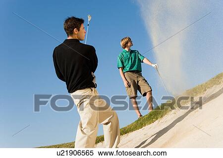 Stock Photography - Golfer hitting ball from sand trap. Fotosearch