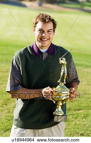 Picture - Golfer holding trophy, (portrait). Fotosearch