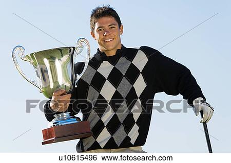 Stock Photograph - Golfer holding trophy, (portrait). Fotosearch