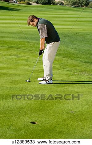 Stock Image - Golfer putting on golf course's green. Fotosearch