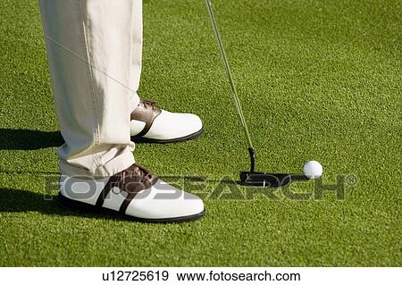 Stock Photo - Golfer putting on green, (low section). Fotosearch