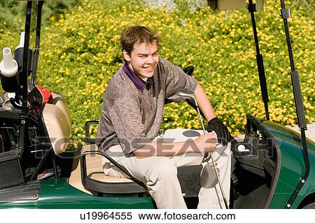 Stock Photography - Golfer sitting in golf cart smiling. Fotosearch