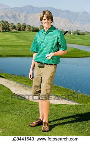 Stock Image - Golfer standing on golf course green, (portrait). Fotosearch
