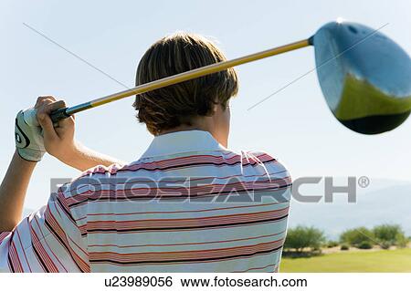 Stock Photograph - Golfer swinging club, back view. Fotosearch