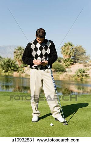 Stock Image - Golfer taking notes on golf course. Fotosearch
