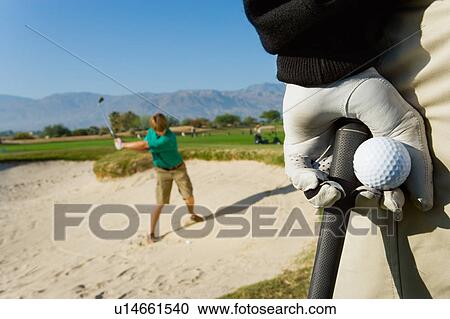 Golfer watching other golfer hit ball from sand trap View Large Photo Image Stock Image - Golfer watching other golfer hit ball from sand trap. Fotosearch