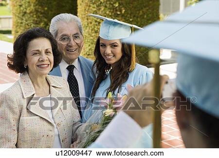 Stock Photo - Graduate and grandparents having photograph taken outside. Fotosearch
