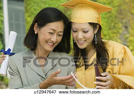 Stock Photo - Graduate and mother admiring necklace gift outside. Fotosearch
