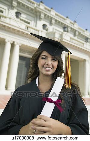 Stock Photo - Graduate holding diploma outside university, portrait. Fotosearch