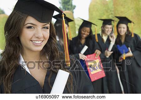 Graduate Holding Diploma outside with others behind, portrait View Large Photo Image Stock Photo - Graduate Holding Diploma outside with others behind, portrait. Fotosearch