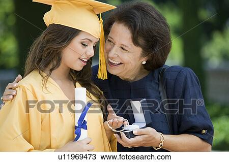 Stock Image - Graduate Receiving bracelet from Grandmother outside. Fotosearch