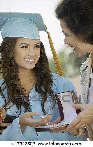 Stock Image - Graduate Receiving necklace from Grandmother outside. Fotosearch