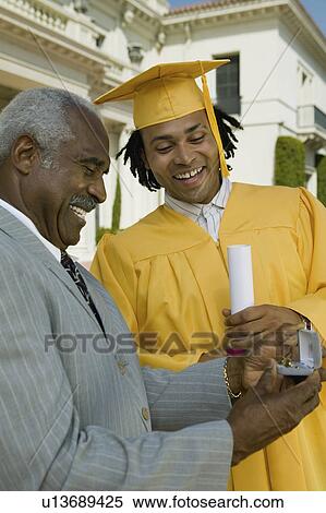 Graduate receiving present from father outside university View Large Photo Image Stock Photography - Graduate receiving present from father outside university. Fotosearch