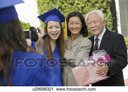 Graduate videotaping other graduate with mother and grandfather outside View Large Photo Image Stock Image - Graduate videotaping other graduate with mother and grandfather outside. Fotosearch