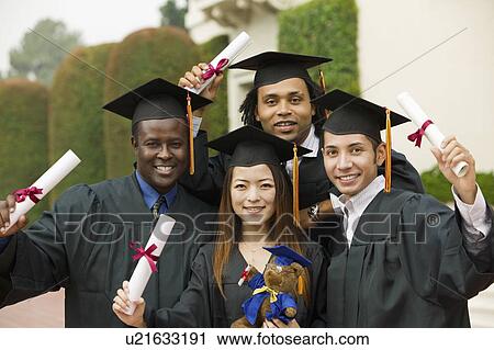 Stock Image - Graduates hoisting diplomas outside, portrait. Fotosearch