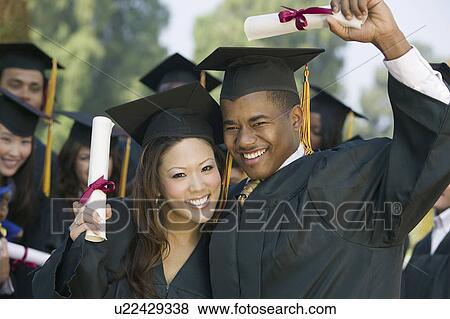 Stock Photo - Graduates hoisting diplomas outside. Fotosearch
