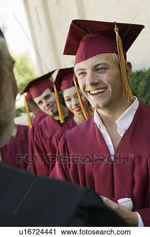 Stock Image - Graduates in line for degree outside. Fotosearch